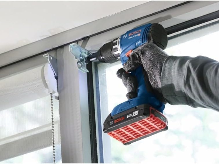 A worker uses the Bosch GSR18V 18V drill driver to install a window blind.