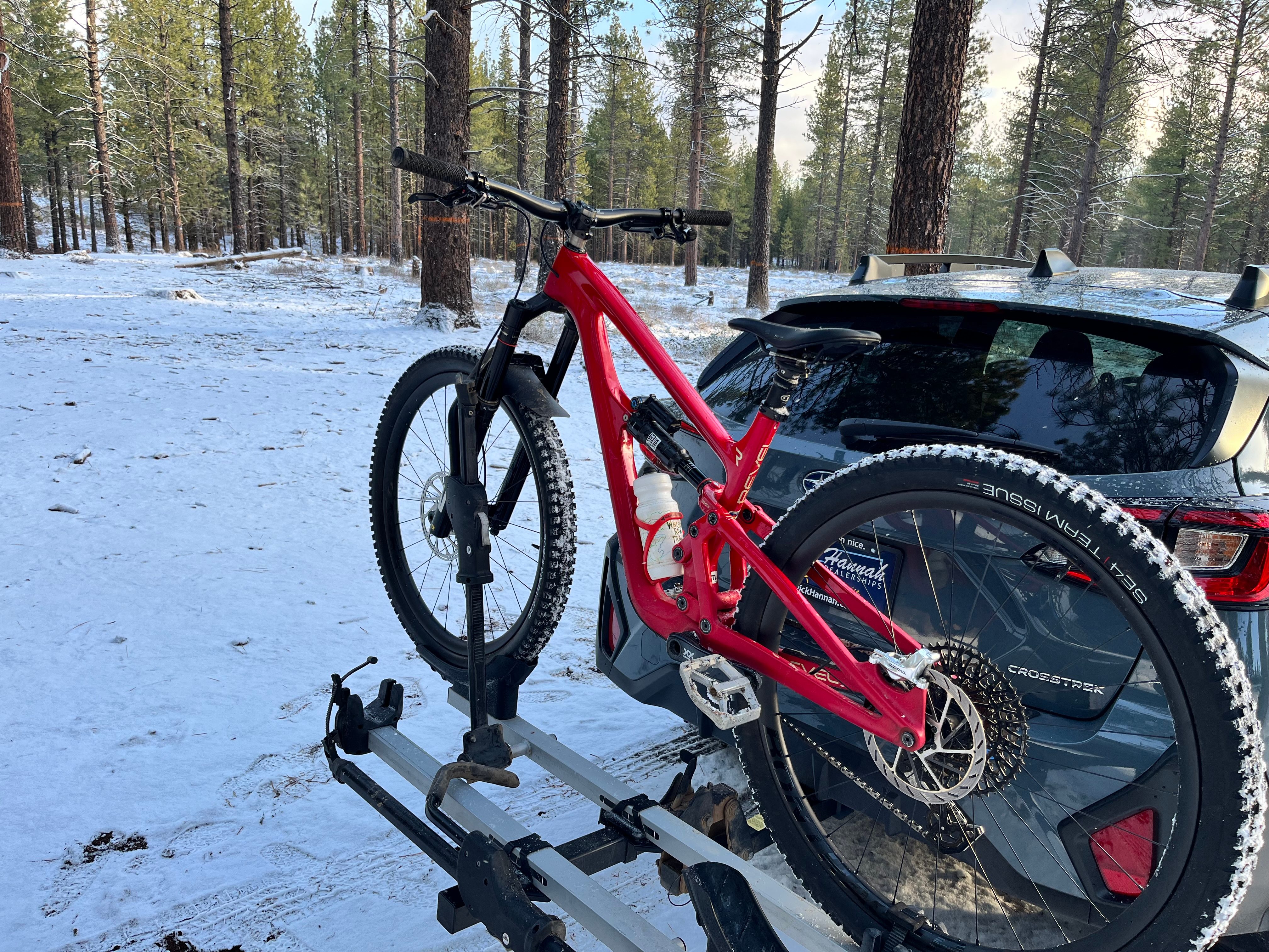 A mountain bike on the bike rack behind a car
