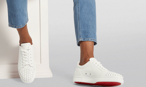 Someone wearing a pair of Louboutin's Junior Spikes Calfskin Sneakers.