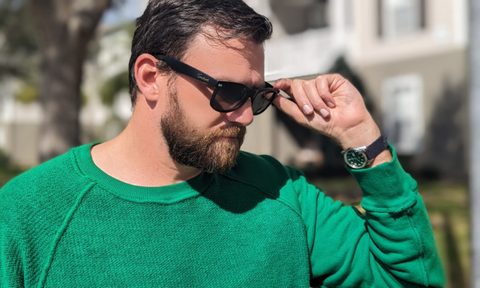 Man in green sweatshirt and sunglasses with watch