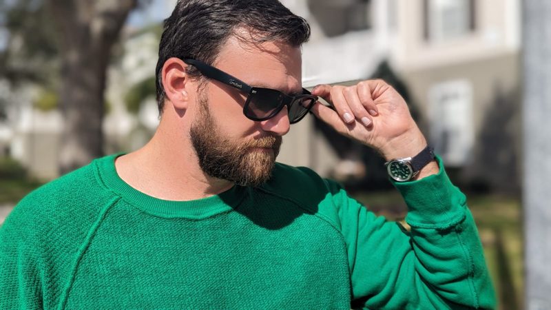Man in green sweatshirt and sunglasses with watch