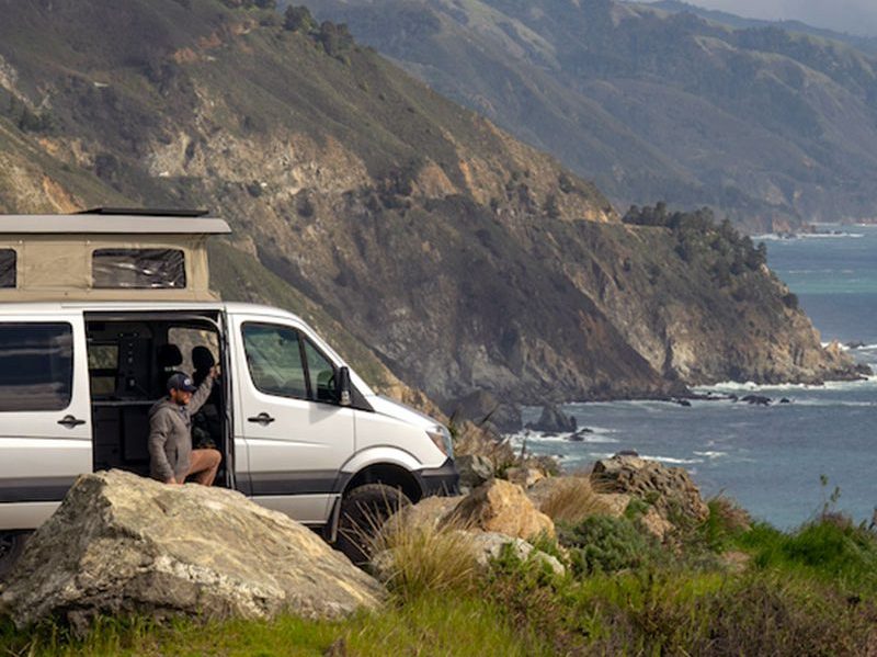 A man takes in a scenic view from a Moterra Campervan.