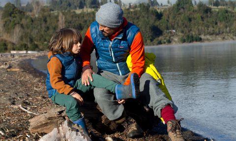 A man and child wearing Patagonia vests by a lake.