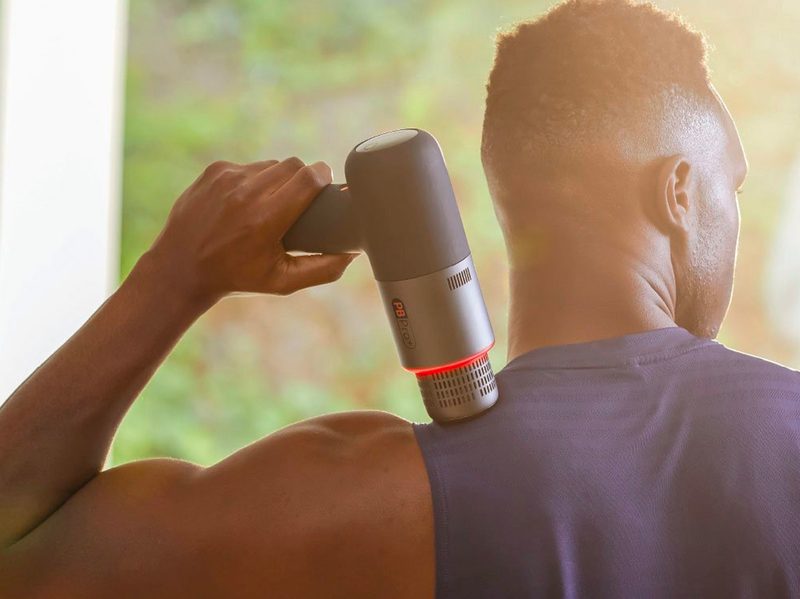 A man uses the Sharper Image Powerboost Pro+ to massage his shoulder.