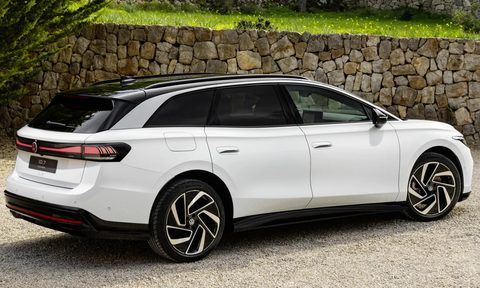 VW ID.7 concept vehicle parked on a stone driveway with a landscaped rock wall in the background right rear three-quarter view of white car.