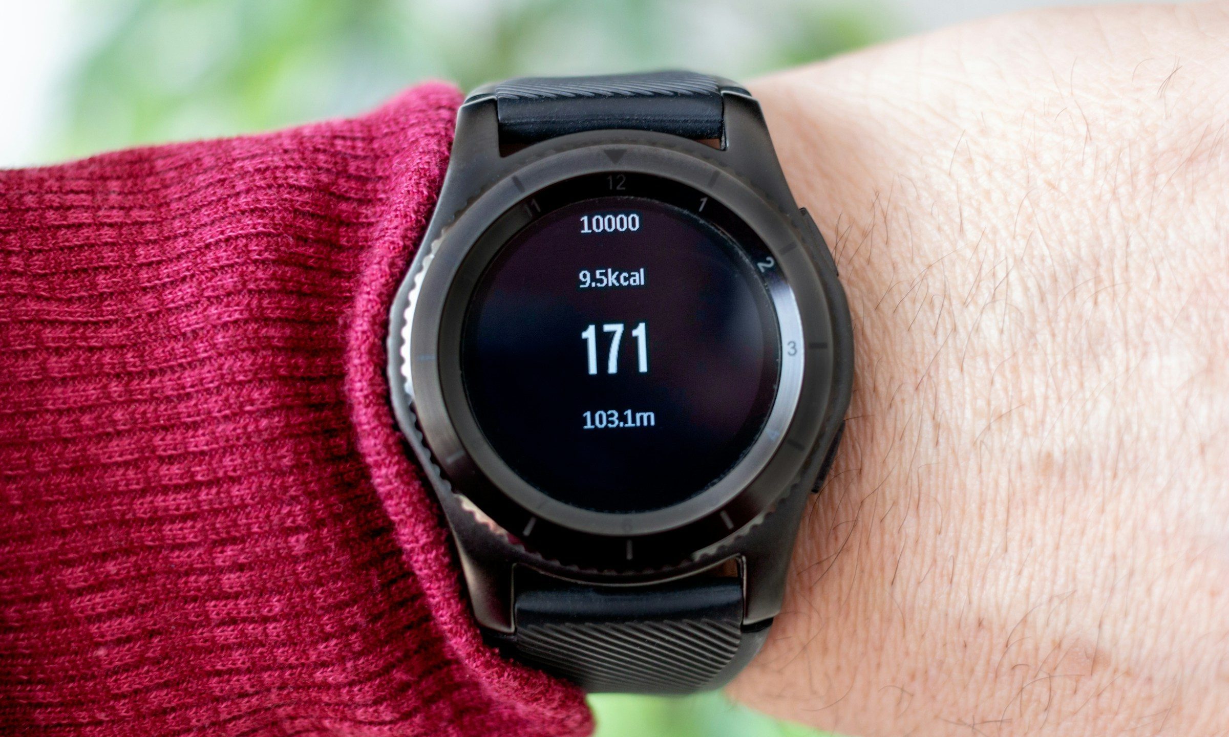 person outside wearing a black smart watch showing calories
