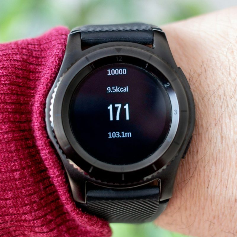 Person outside wearing a black smart watch showing calories