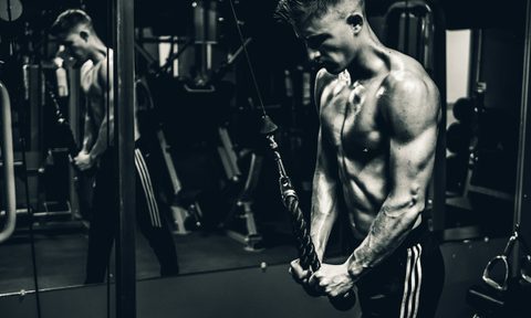 Black and white picture man shirtless doing cable pushdown exercise in the gym