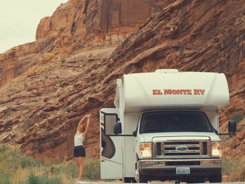 A woman stretching amidst canyons outside an El Monte RV.