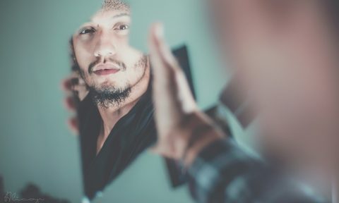 man looking into a mirror with teal paint
