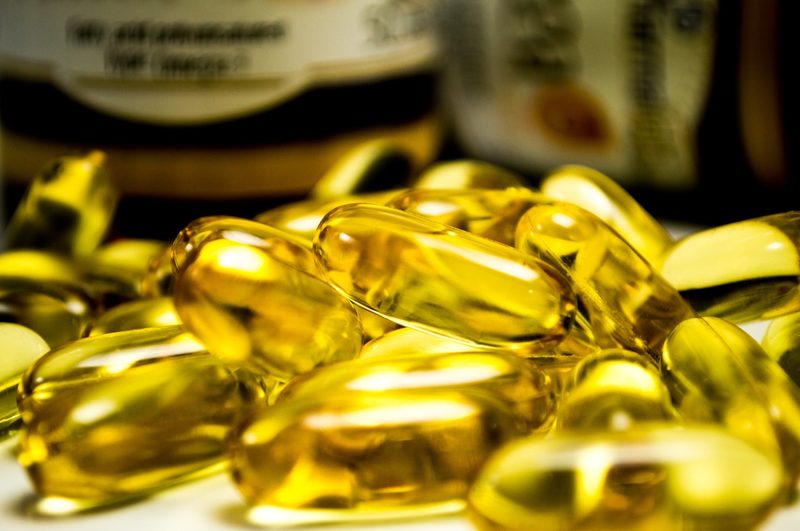 Golden fish oil supplements up close in a pile