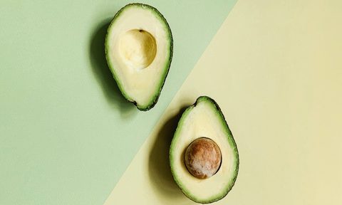 Avocado cut in half bird's-eye view on green and yellow background