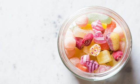 candy sugary colorful treats in glass jar on white table