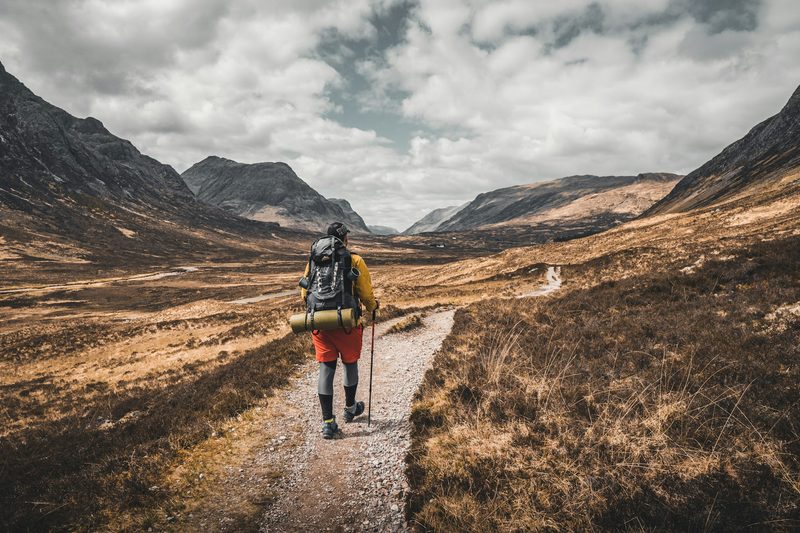 A hiker heading out on a trail in an open field.