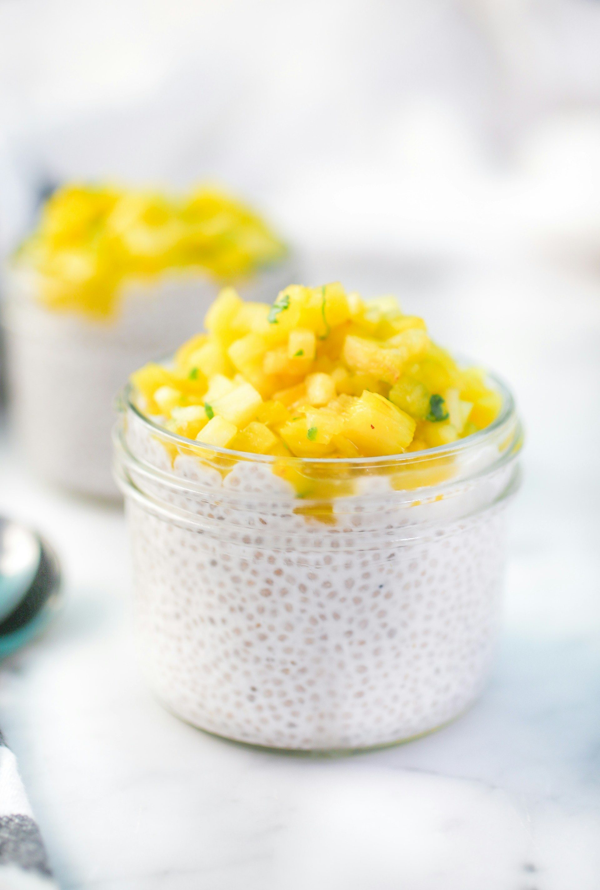 Glass jar of chia seed pudding with fruit on white table