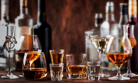 Strong Spirits Set. Hard alcoholic drinks in glasses in assortment: vodka, cognac, tequila, brandy and whiskey, grappa, liqueur, vermouth, tincture, rum. Vintage bar counter background, selective focus