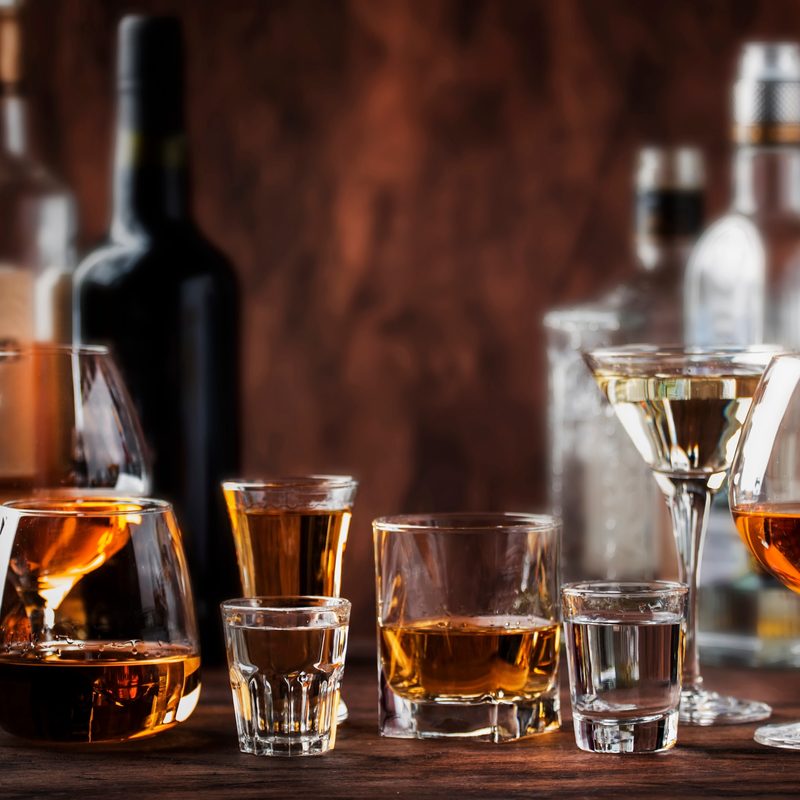 Strong Spirits Set. Hard alcoholic drinks in glasses in assortment: vodka, cognac, tequila, brandy and whiskey, grappa, liqueur, vermouth, tincture, rum. Vintage bar counter background, selective focus