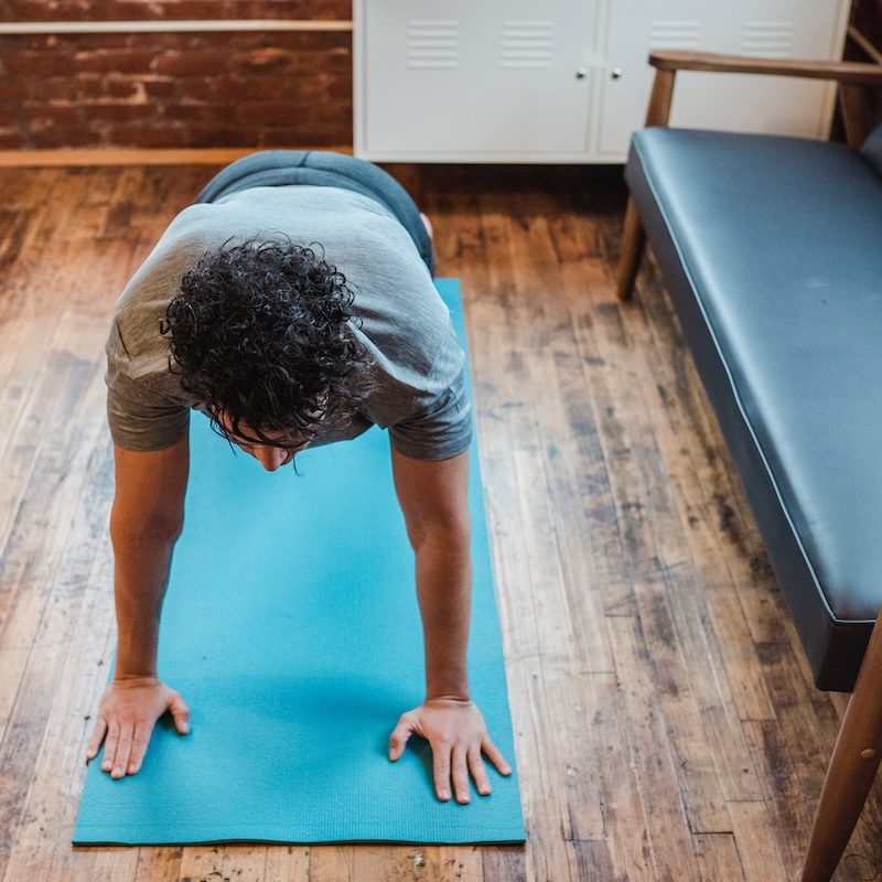 A man on a bright blue mat doing a plank