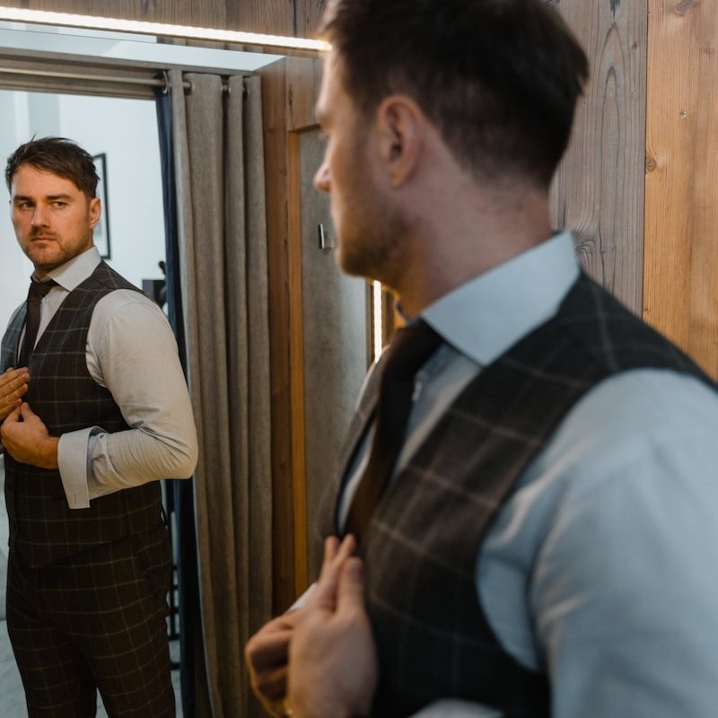 A man in a suit looking in a mirror