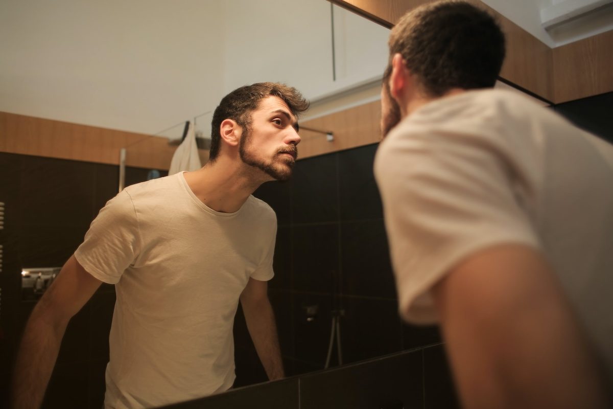a man looking in the bathroom mirror