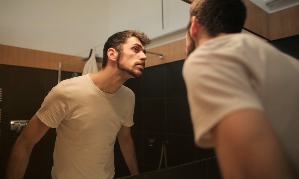 A man looking in the bathroom mirror