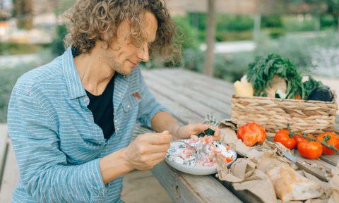 Person eating a meal on a picnic table outside