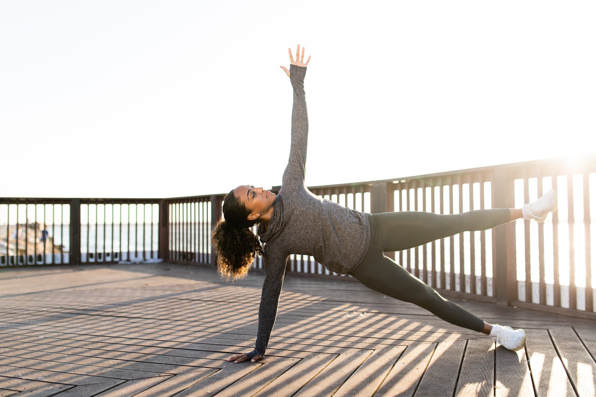 woman doing side bend pilates move outside on deck