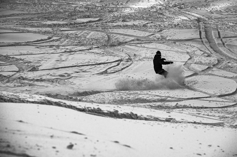 snowboarder riding through powder field