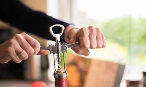 Person opening wine bottle