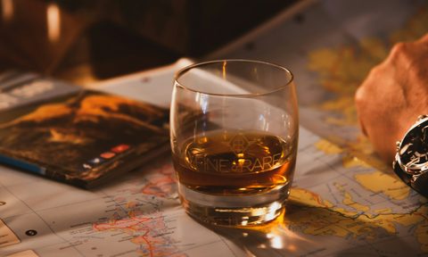 Whiskey in a glass next a person