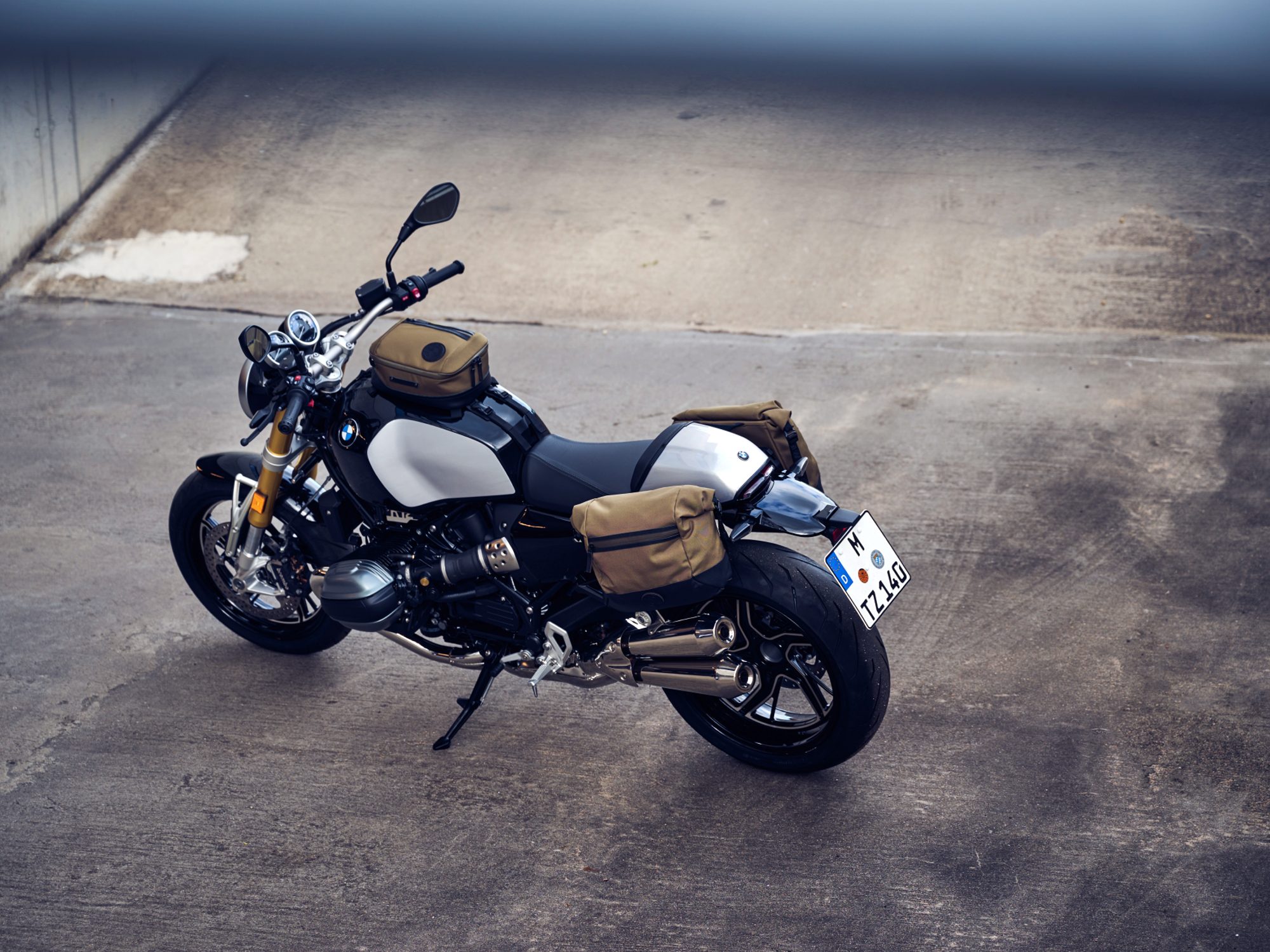 A parked 2024 BMW R 12 NineT with a light tan tank bag and matching small saddlebags.