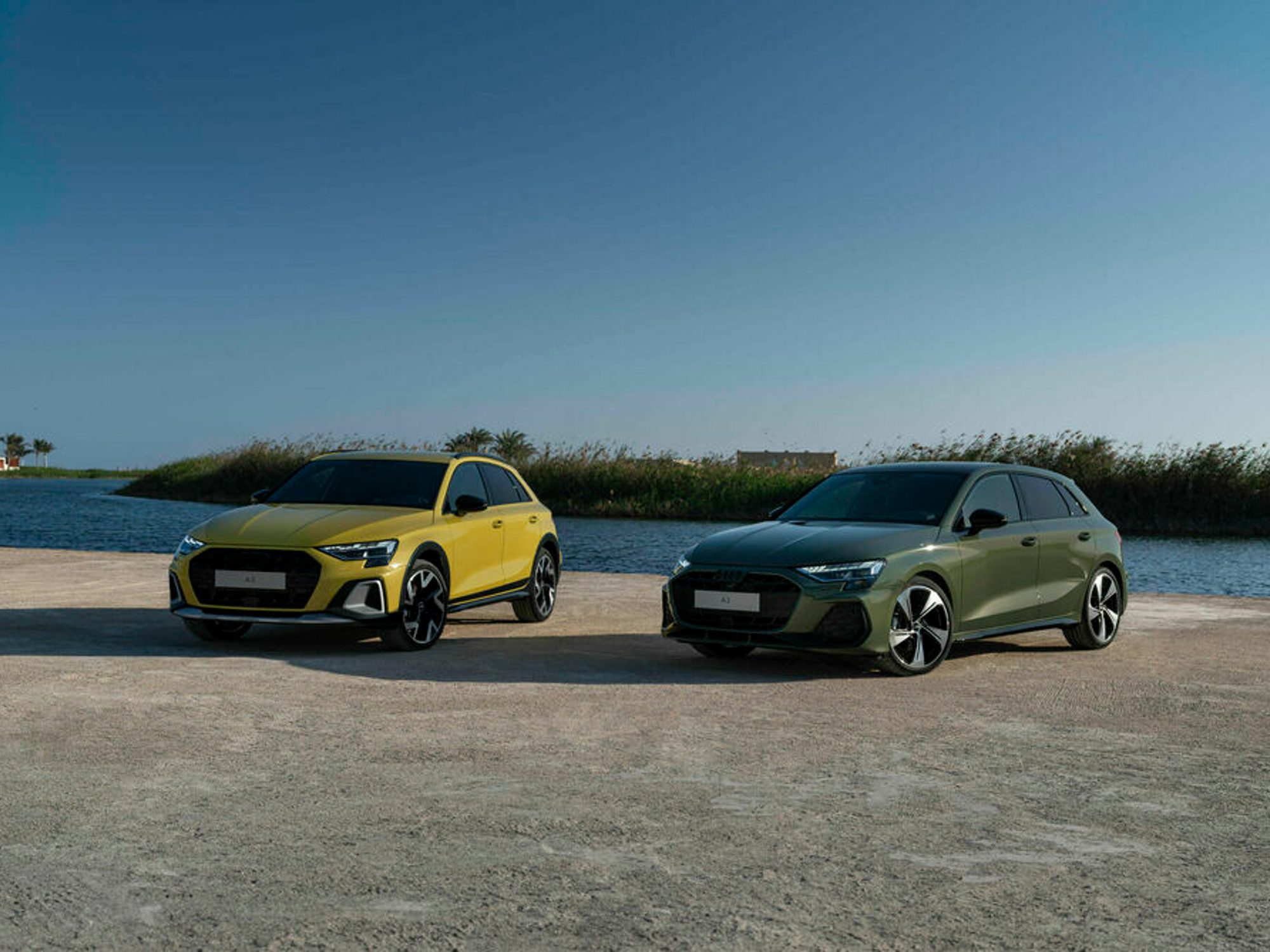 Audi A3 Allstreet and Audi A3 Sportback Sportback parked on a beach with water and a barrier island in the background.
