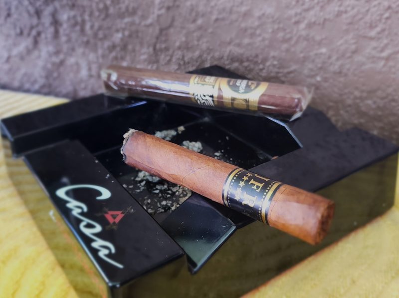 JFR Maduro cigar up close and lit with Aganorsa Rare Leaf Reserve Maduro behind