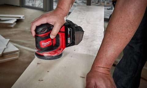 Someone using the Milwaukee Orbit Sander in a warehouse.