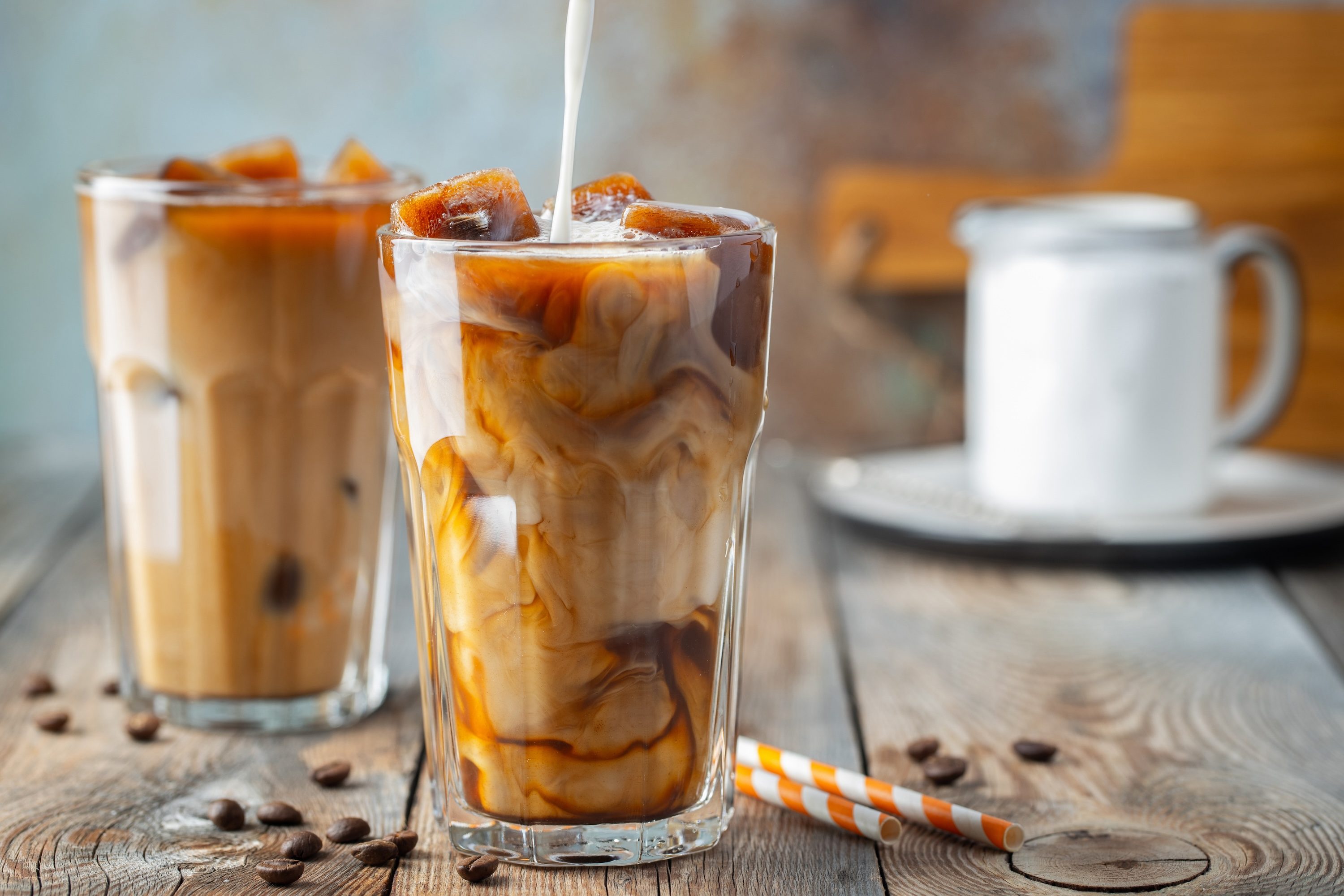 Iced coffee in a tall glass with cream poured over