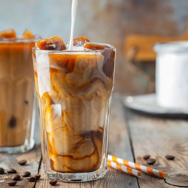 Iced coffee in a tall glass with cream poured over