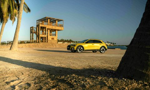 Yellow Audi A3 Allsteet parked on a beach with a lifeguard station and palm trees.