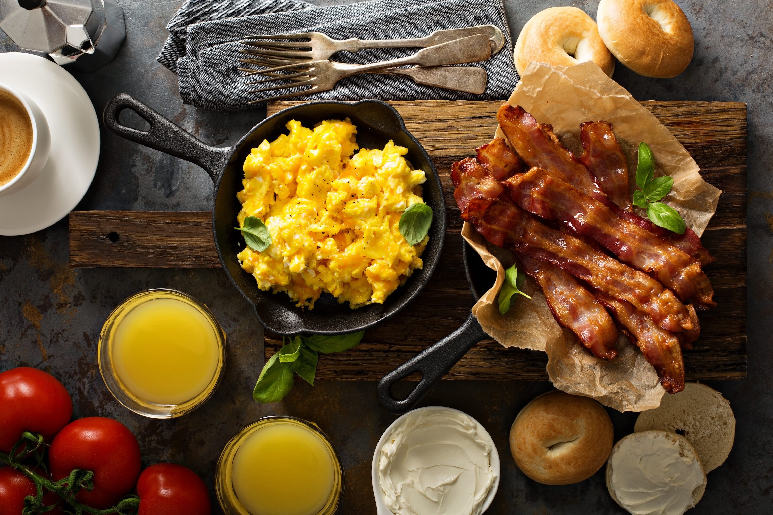 Big breakfast with bacon, bagels and scrambled eggs on the table overhead