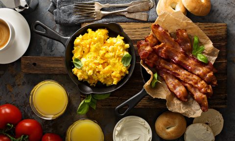 Big breakfast with bacon, bagels and scrambled eggs on the table overhead