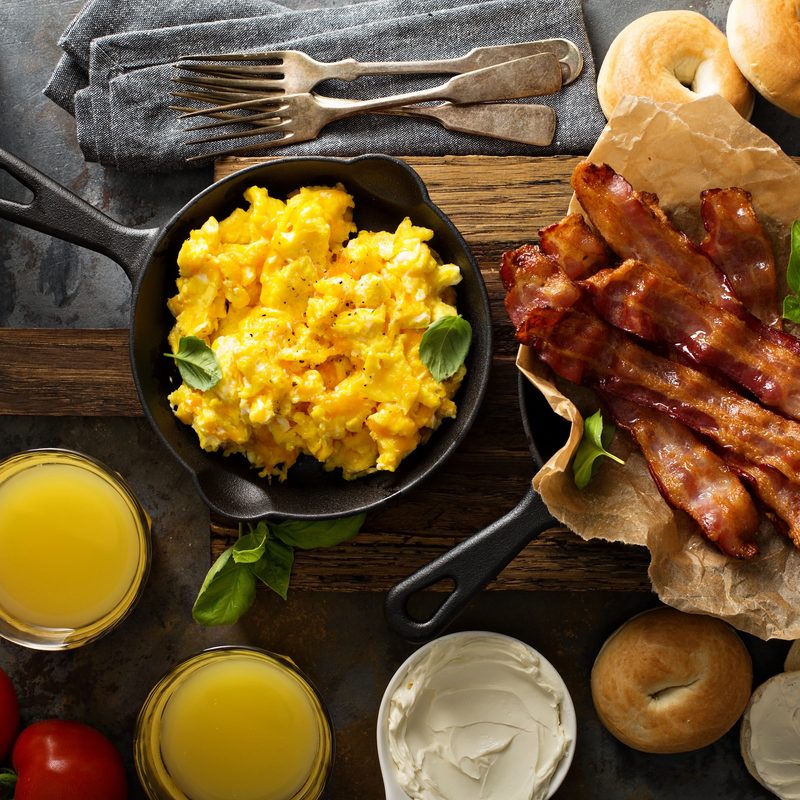 Big breakfast with bacon, bagels and scrambled eggs on the table overhead