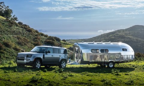 Bowlus Rivet travel trailer being towed by an SUV through a grassy field.