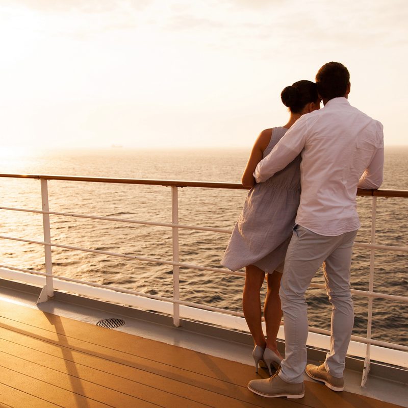 back view of young couple hugging at sunset on cruise ship