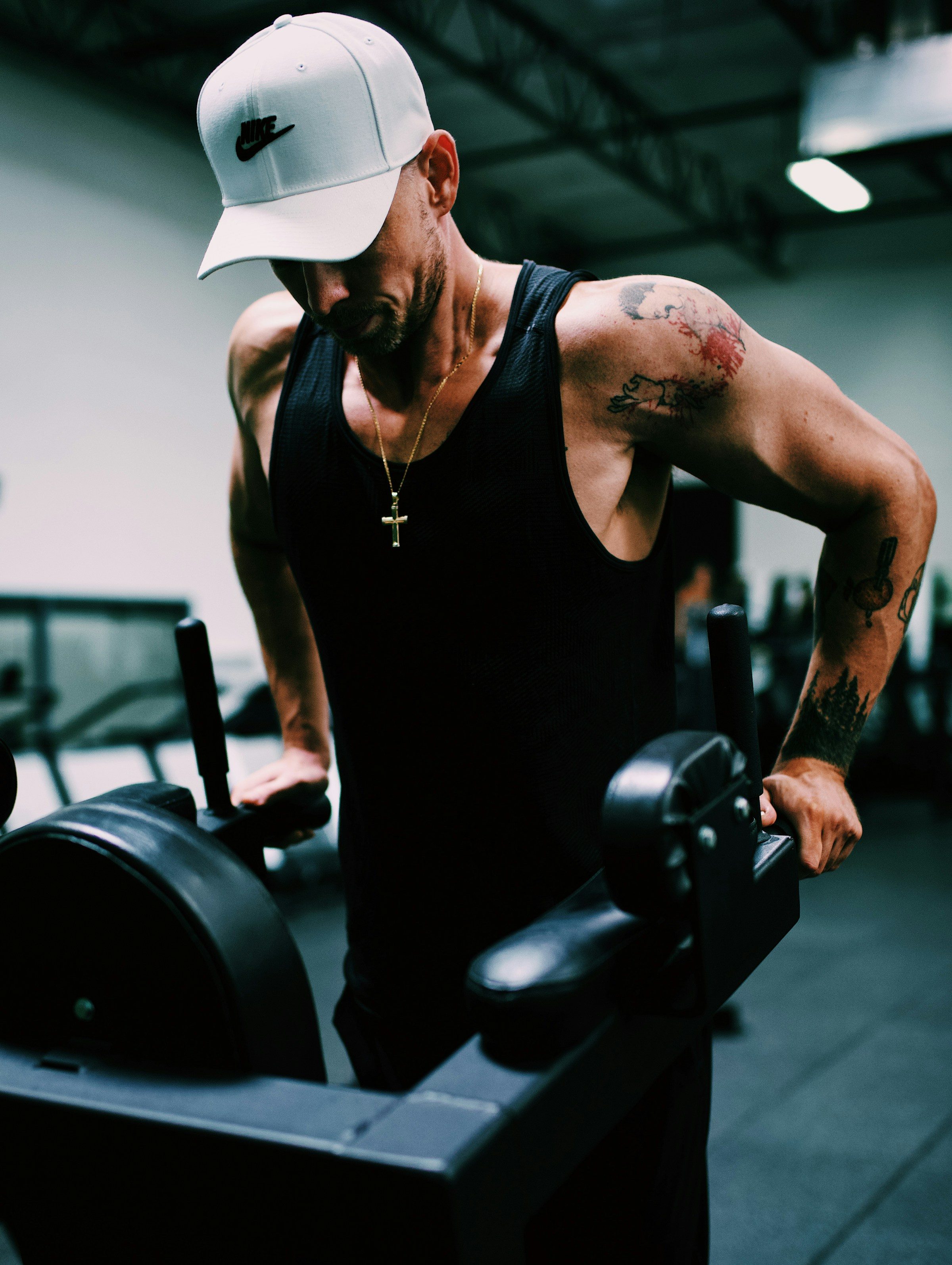 man doing dips exercise wearing white hat in gym on gym machine