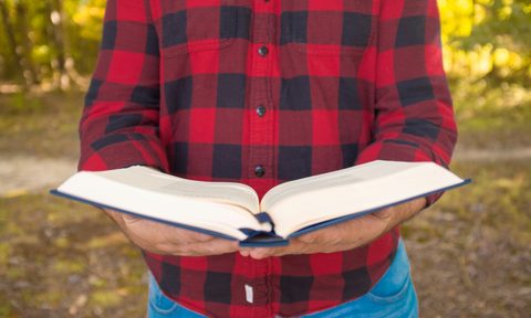 man in flannel holding a book