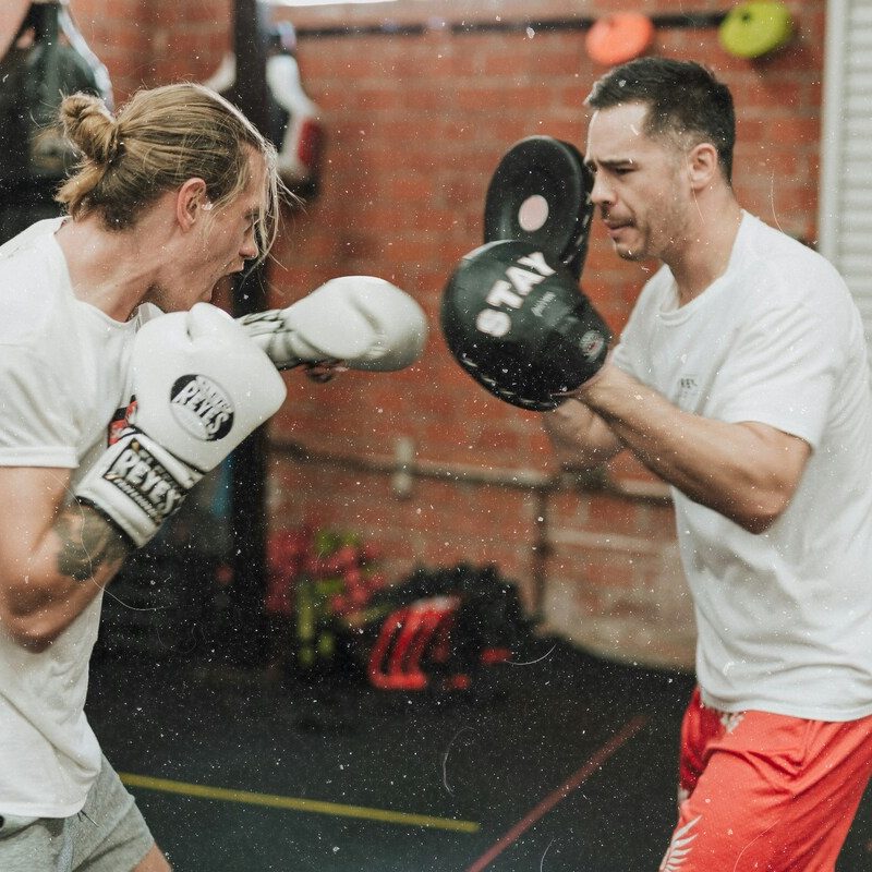 Man boxing with trainer.