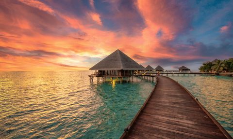 dock leading to an overwater bungalow in the ocean
