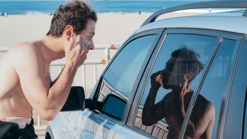 Mman applying sunscreen in front of car