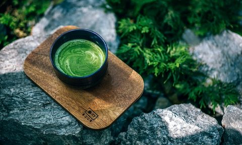 a cup of green tea on a cutting board