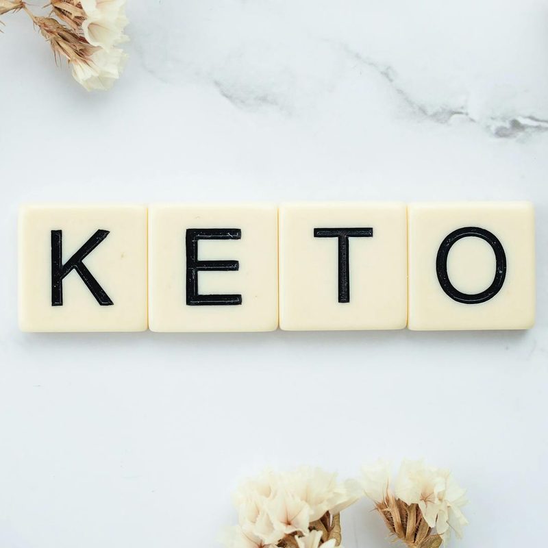 keto text blocks on white stone background with white flowers word keto