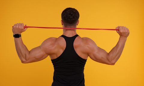 resistance band back exercises young man exercising with elastic on orange background  view